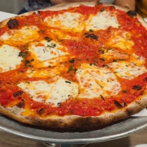 A whole Marco Pizzeria Margherita pizza with fresh mozzarella, tomato sauce, and basil on a metal tray.