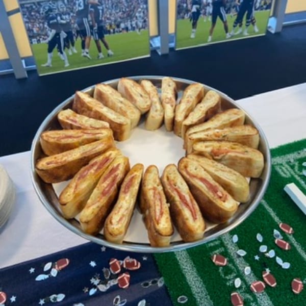 A platter of sliced stromboli arranged in a circle, with football-themed decorations on the table.